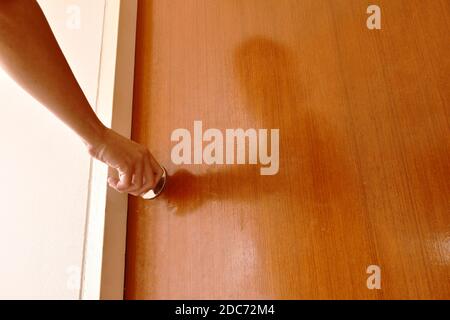 hand twisting silver knob to opened wooden door in home Stock Photo