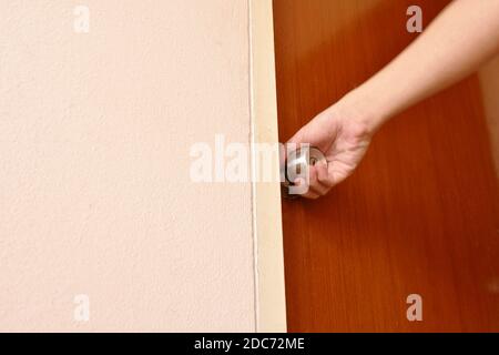 hand twisting silver knob to opened wooden door in home Stock Photo