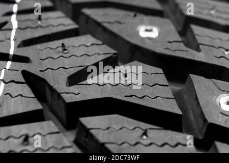Macro shot winter studded tire. Winter car tires texture. Tyre protector close up. Square powerful spikes. Black studdable winter tyre profile. Car ti Stock Photo