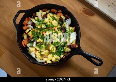 vegetable pan with potatoes, onions and fresh herbs in a cast iron grill pan Stock Photo