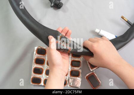 teenager hands holding inflatable chamber for wheels bicycle  with patch glued on Stock Photo