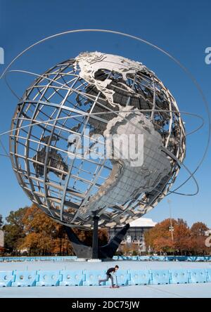 On a mild autumn day, a boy, rides a scooter around the perimeter of the Unisphere in Flushing Meadows Corona Park in Queens, New York City