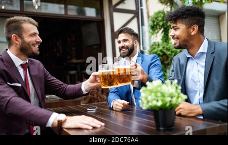 Cheerful old friends having fun and drinking beer at bar counter in pub. Stock Photo