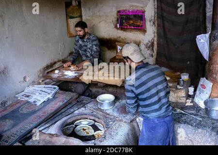 Two men working in bakery with stone ovens, Leh, Ladakh, India Stock Photo