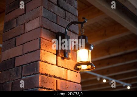 rustic lamp shines with light bulb on a brick wall Stock Photo