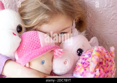 Happy little blonde girl playing with her toys Stock Photo