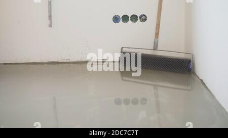 Charcoal roller on the self-leveling floor. Charcoal roller. Self-leveling floor tool. Self-leveling epoxy. Leveling with a mixture of cement floors Stock Photo