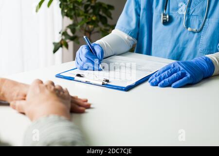 General Practitioner completing patient examination in doctor's office,filling out medical card form,diagnostic consultation & prevention of women's d Stock Photo