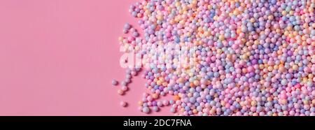 Pile of pastel color balls on pink. Styrofoam or Polystyrene foam background. Mix of colorful sugar balls, used to decorate baking and sweets. Rainbow Stock Photo