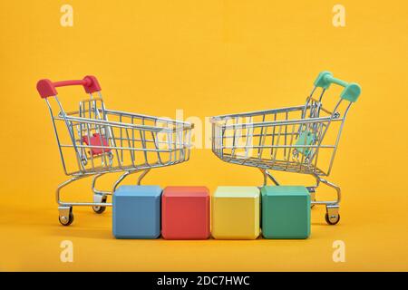 empty wooden cubes mockup style, copy space with shopping trolleys on yellow background. Colourful blocks template for creative design, place for text Stock Photo