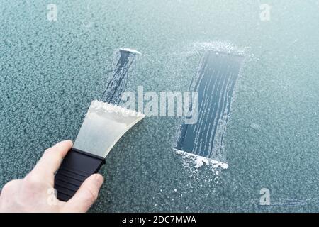 frosted car glass. Frosty patterns on a car windscreen . scraper for cleaning glass from ice Stock Photo