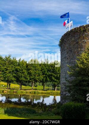 Stone tower and avenue of trees reflected in water at Le Haut-Corlay in Western Brittany France with French and European Union flags flying on a pole. Stock Photo