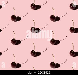 Seamless pattern with cherry berries on pink background in sun light. Summer food pattern. Stock Photo