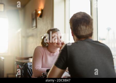 Positive young couple chatting and laughing while sitting at table in cafe Stock Photo