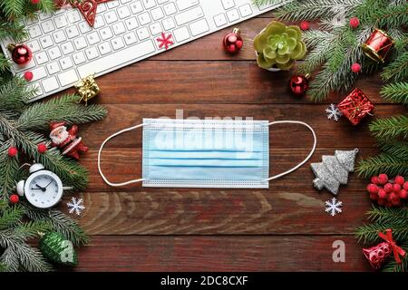 Christmas background with fir branches, keyboard, medical mask on wooden board  Stock Photo