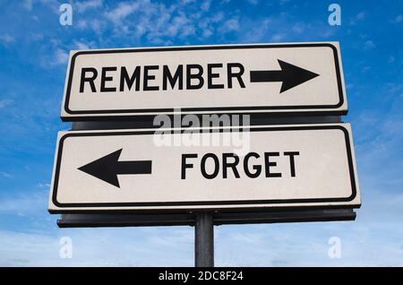 Remember versus forget road sign. White two street signs with arrow on metal pole with word. Directional road. Crossroads Road Sign, Two Arrow. Blue s Stock Photo