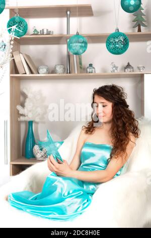 A girl in a blue dress admires the Christmas star against the background of New Year's decorations Stock Photo