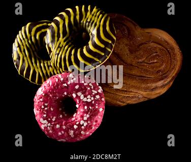 American brown and pink donuts and baked bun on black background Stock Photo