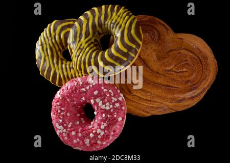 American brown and pink donuts and baked bun on black background Stock Photo