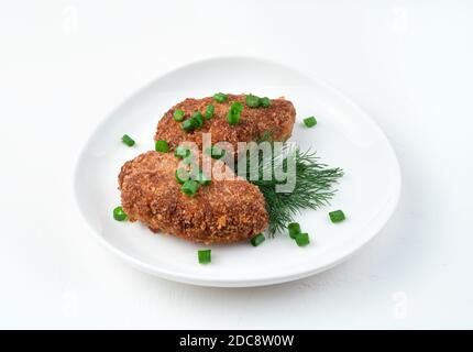 White plate with fried cutlets and herbs on a white background. Stock Photo