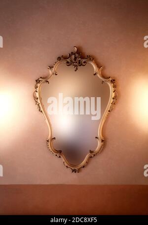 Old fashioned luxury gold colored frame mirror antique design, hanging on vintage wall background texture, blurred mirror, copy space Stock Photo