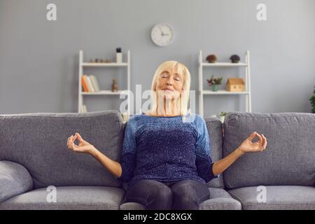 Happy relaxed senior woman practising meditation and stress relief exercise at home Stock Photo