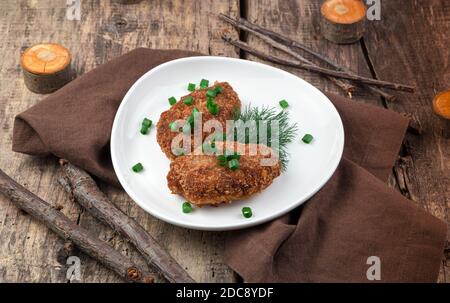 Meat cutlets in a plate on a natural wooden background. Stock Photo