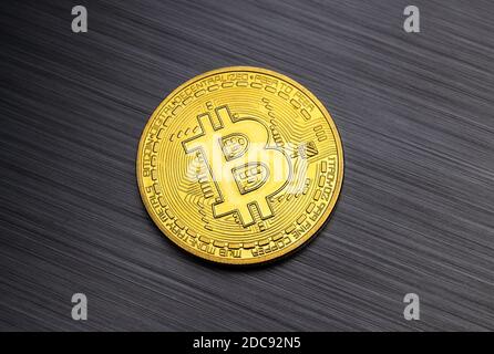 Golden bitcoin token isolated on brushed metal background Stock Photo