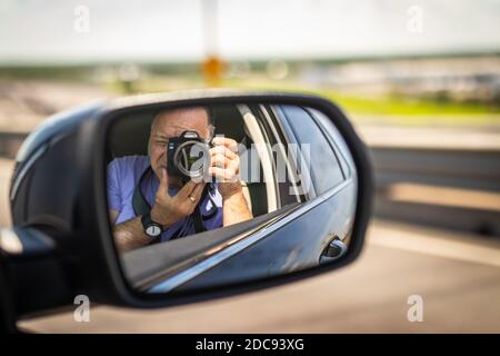 middle aged man taking self portrait in wing mirror in Florida USA Stock Photo