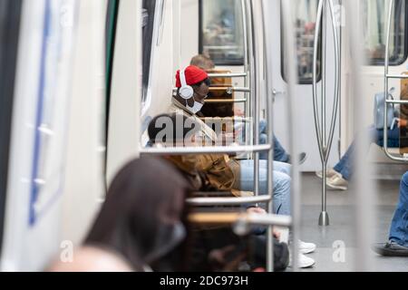 Afro-American passenger man sitting in subway train, wear face medical mask to protect yourself from contact with flu virus, covid-19, using mobile ph Stock Photo