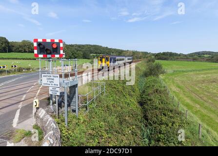 Silverdale automatic half barrier  ( AHB ) level crossing Lancashire with a Northern Rail class 156 train approaching Stock Photo