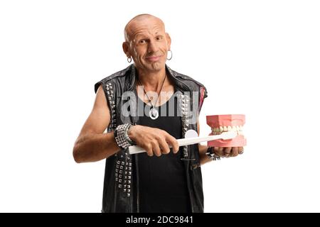 Bald punk brushing teeth on a jaw model with a big toothbrush isolated on white background Stock Photo