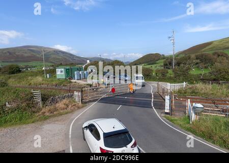 Manually operated railway level crossing on a rural road and railway line being closed to road traffic with cars waiting Stock Photo