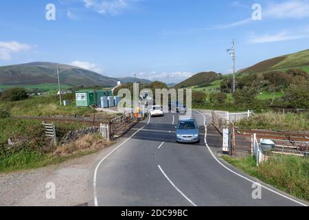 Manually operated railway level crossing on a rural road and railway line with cars crossing after the gates had been opened to road traffic Stock Photo