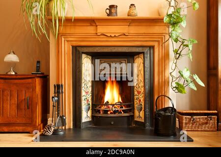 Cosy winter living room fireplace, with open fire with real flames burning coal, UK home interior Stock Photo