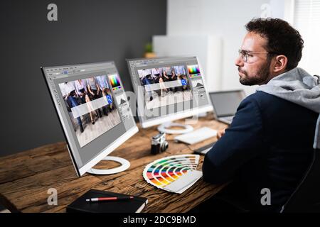 Designer Editing Photos On Multiple Computer Screens Stock Photo