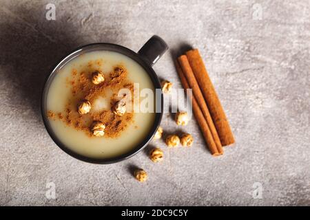 Boza or Bosa, traditional Turkish drink with roasted chickpea in ceramic bowl with cinnamon on stone background. Stock Photo
