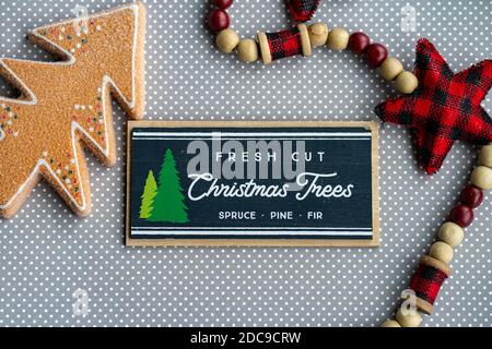 Fresh cut Christmas trees sign with red plaid fabric stars and gingerbread tree on grey polka dot background, for Christmas projects Stock Photo