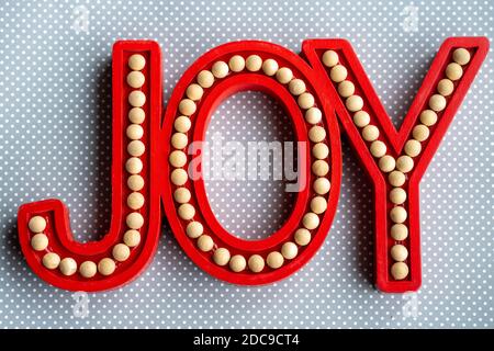 Red Joy word letters on a gray white polka dot wood background, useful for rustic Christmas holiday projects Stock Photo