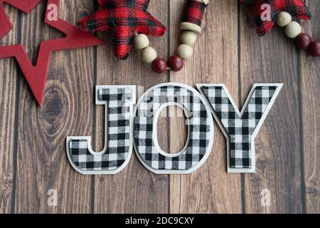 Black and white joy plaid phrase on a wood background with red stars, useful for Christmas projects Stock Photo