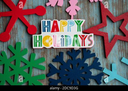 Happy Holidays with rainbow colored snowflakes, on a teal wood background. Useful for Christmas projects Stock Photo