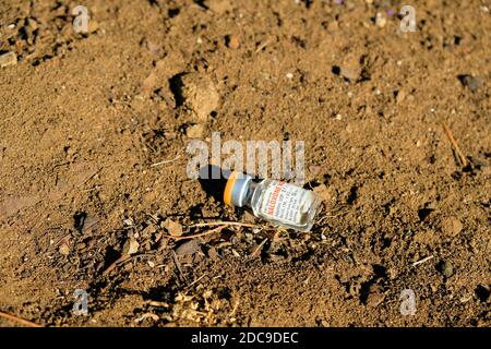 Naloxone HCL vial in the dirt on the ground; opioid antagonist used for the treatment of known or suspected opioid overdose; opioid effect blocker. Stock Photo