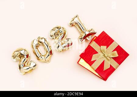 Foil balloons in the form of numbers 2021 and gift box. New year celebration. Holiday party decoration. Stock Photo