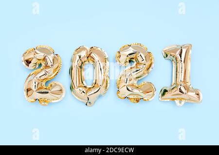 Foil balloons in the form of numbers 2021 on blue background. New year celebration. Gold Air Balloons. Holiday party decoration. Top view Stock Photo
