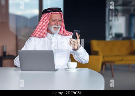 Arab businessman laptop computer in modern office using phone Stock Photo