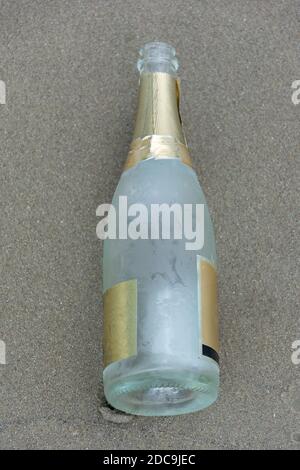 Empty sparkling bottle on the beach sand. Stock Photo