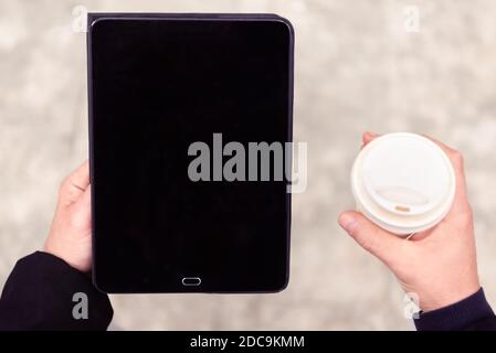 close up portrait of a business man holding a tablet device and carrying his coffee during a work meeting break.background up view image of a pad Stock Photo