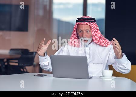 Arab businessman looks surprised while using a laptop Stock Photo
