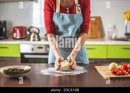 A female chef is kneading dough with her hands in the kitchen for making homemade pizza. Stock Photo