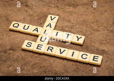 value, quality and service crossword in ivory letter tiles against textured handmade paper, business and core values concept Stock Photo